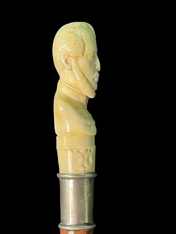 Cane with an ivory knob depicting a male bust. The shaft is made of rattan.