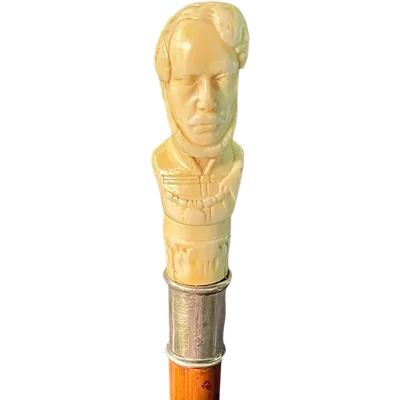 Cane with an ivory knob depicting a male bust. The shaft is made of rattan.