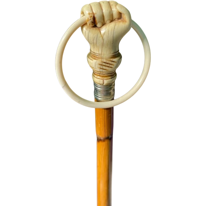 A walking stick with an ivory knob depicting a hand clutching a ring (glove holder).l