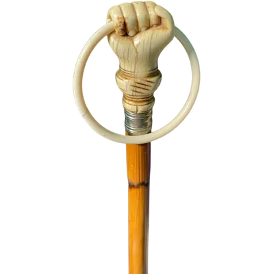 A walking stick with an ivory knob depicting a hand clutching a ring (glove holder).l