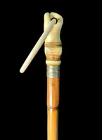 A walking stick with an ivory knob depicting a hand clutching a ring (glove holder).l