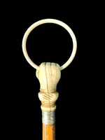 A walking stick with an ivory knob depicting a hand clutching a ring (glove holder).l