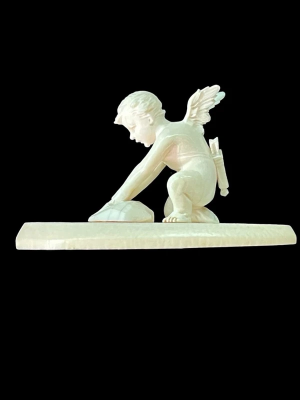Petite sculpture en ivoire représentant Cupidon en train d'aiguiser