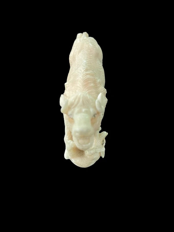 Scultura in avorio raffigurante un bisonte attaccato da due lupi.