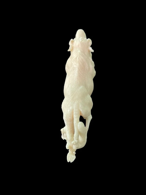 Scultura in avorio raffigurante un bisonte attaccato da due lupi.