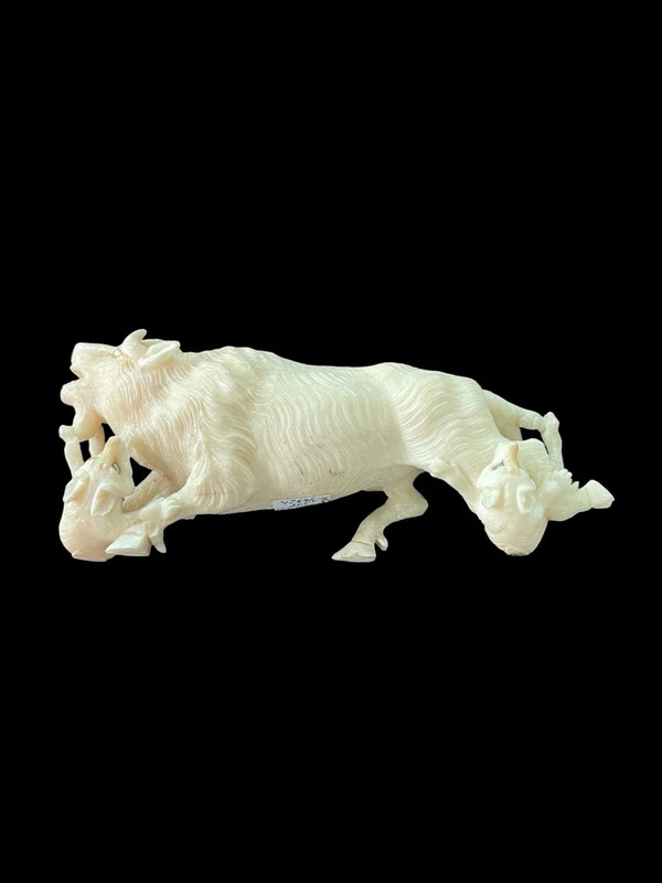 Scultura in avorio raffigurante un bisonte attaccato da due lupi.