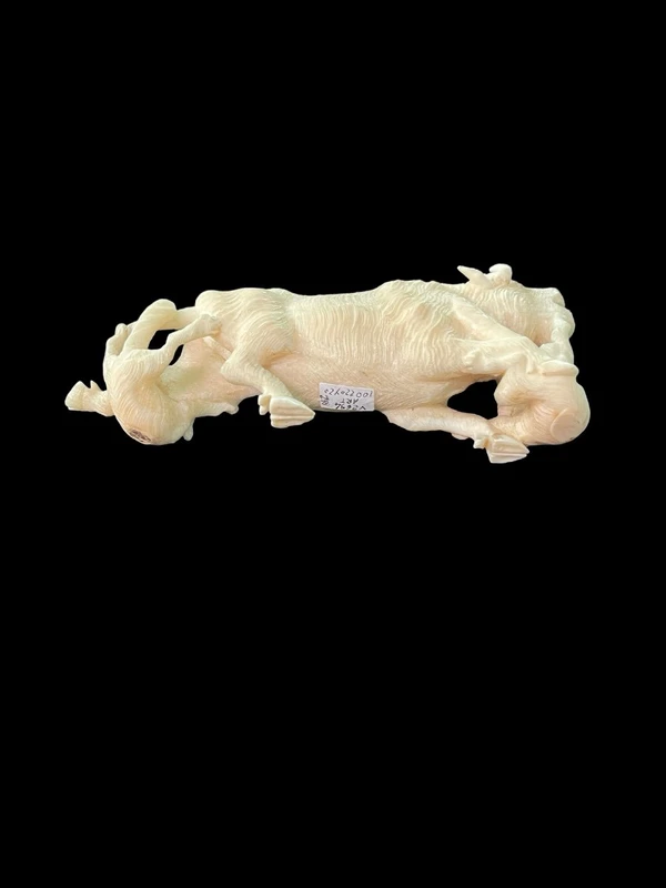 Scultura in avorio raffigurante un bisonte attaccato da due lupi.