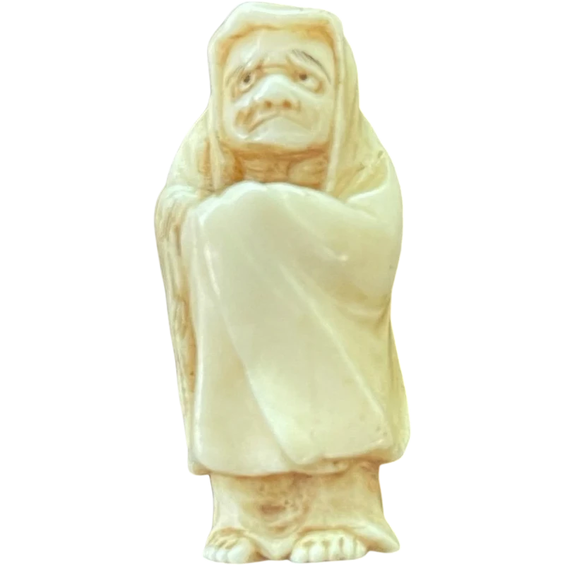 Ivory netsuke depicting a male figure wearing a cloak. Japan.