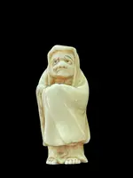 Ivory netsuke depicting a male figure wearing a cloak. Japan.