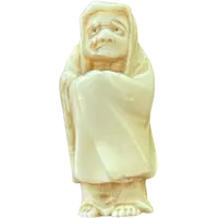 Ivory netsuke depicting a male figure wearing a cloak. Japan.