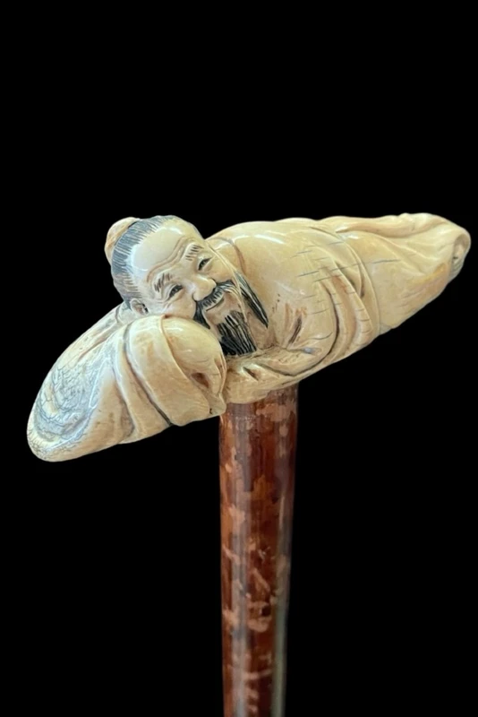 Bâton avec un manche en ivoire représentant un Japonais allongé.