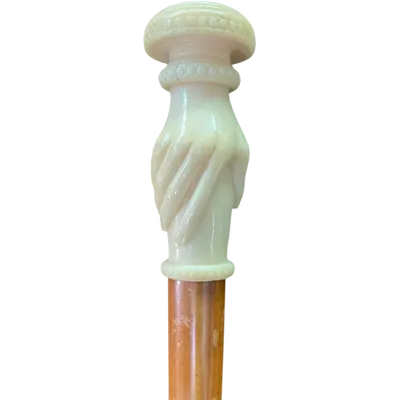 A walking stick with an ivory handle depicting a hand clutching a knob.
