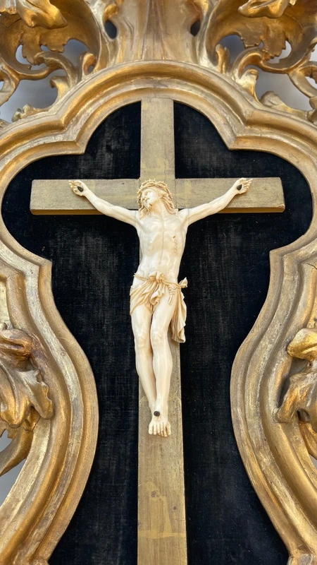 Christ en ivoire, dans un cadre en forme de cartouche en bois sculpté et doré à la feuille.