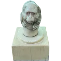 Petite sculpture en ivoire (poignée de canne) posée sur un socle carré et représentant un singe.