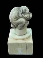 Petite sculpture en ivoire (poignée de canne) posée sur un socle carré et représentant un singe.