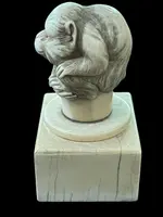 Petite sculpture en ivoire (poignée de canne) posée sur un socle carré et représentant un singe.