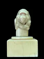 Petite sculpture en ivoire (poignée de canne) posée sur un socle carré et représentant un singe.