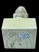Petite sculpture en ivoire (poignée de canne) posée sur un socle carré et représentant un singe.