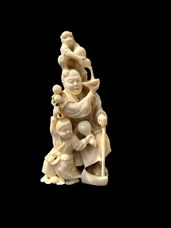Sculpture okimono en ivoire représentant un personnage masculin avec un enfant et un singe.