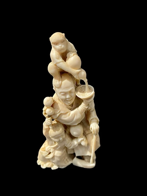 Sculpture okimono en ivoire représentant un personnage masculin avec un enfant et un singe.