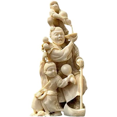An okimono sculpture carved from ivory depicting a man with a boy and a monkey.