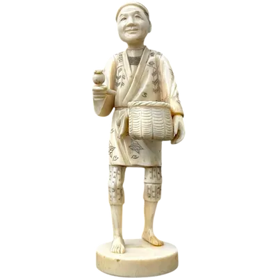 An okimono sculpture carved from ivory depicting a male figure carrying a basket.