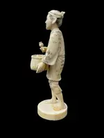 Sculpture okimono en ivoire représentant un personnage masculin portant un panier.