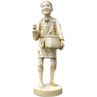 Sculpture okimono en ivoire représentant un personnage masculin portant un panier.