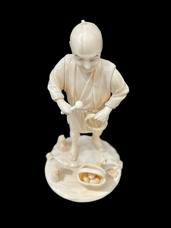 Scultura okimono in avorio raffigurante personaggio maschile con treccia e cesto.