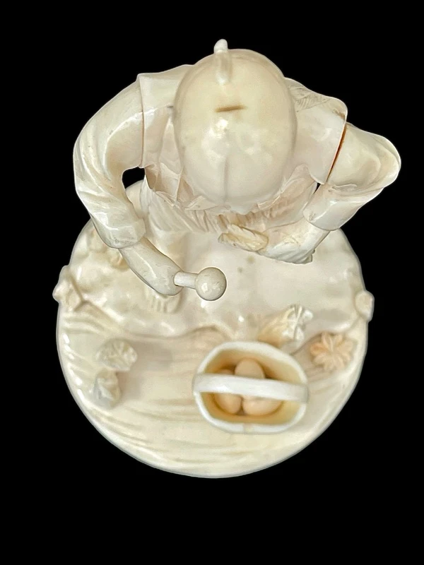 Scultura okimono in avorio raffigurante personaggio maschile con treccia e cesto.