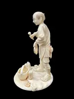 Scultura okimono in avorio raffigurante personaggio maschile con treccia e cesto.