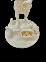Scultura okimono in avorio raffigurante personaggio maschile con treccia e cesto.