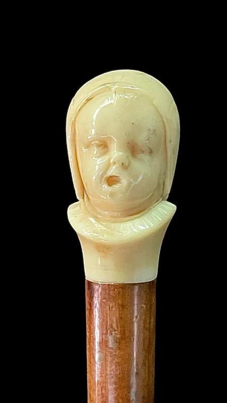 Canne dont le pommeau en ivoire représente le double visage d'un enfant qui rit et qui pleure.