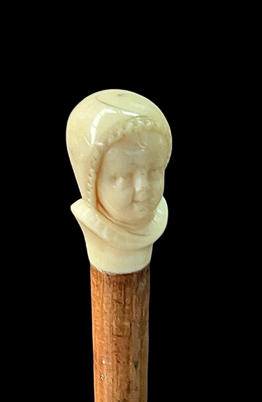 Canne dont le pommeau en ivoire représente le double visage d'un enfant qui rit et qui pleure.