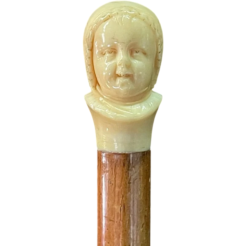 Canne dont le pommeau en ivoire représente le double visage d'un enfant qui rit et qui pleure.