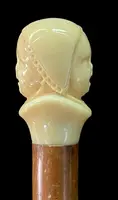 Canne dont le pommeau en ivoire représente le double visage d'un enfant qui rit et qui pleure.