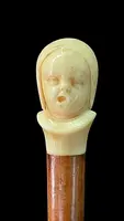 Canne dont le pommeau en ivoire représente le double visage d'un enfant qui rit et qui pleure.