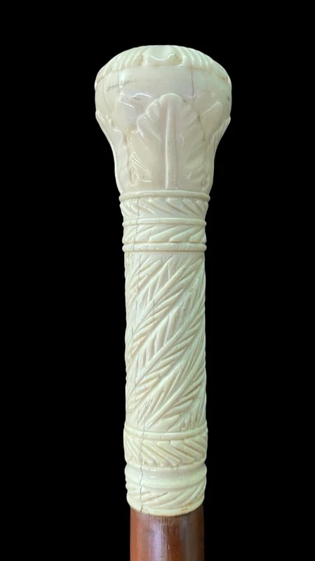 Bastone con pomolo globulare inciso con motivi vegetali e geometrici stilizzati.