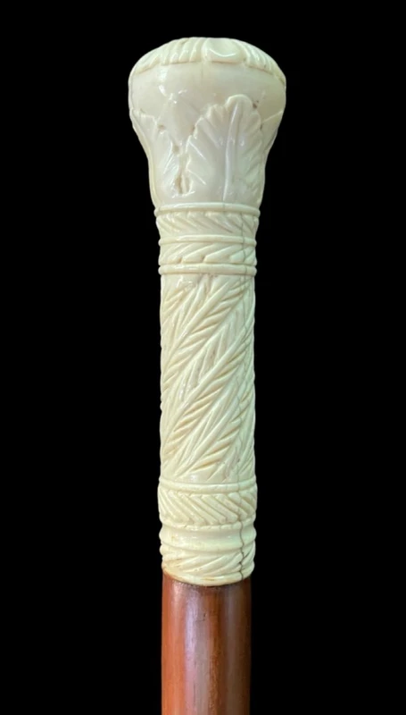 Bastone con pomolo globulare inciso con motivi vegetali e geometrici stilizzati.