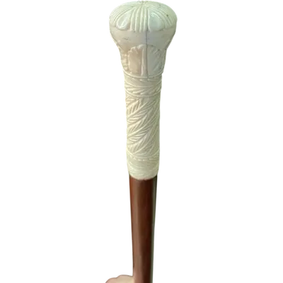 A walking stick with a spherical pommel engraved with stylized plant and geometric motifs.