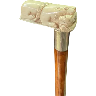 A walking stick with a side handle made of ivory, depicting a lion and a snake.
