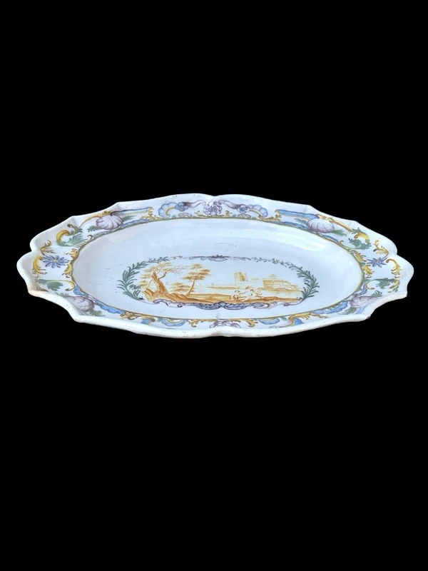 Oval plate with a lobed rim and a border decorated with plant motifs and rocaille.