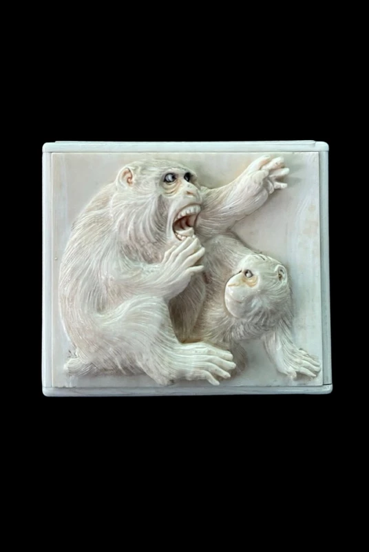 A small ivory box with a lid engraved with two monkeys in high relief.