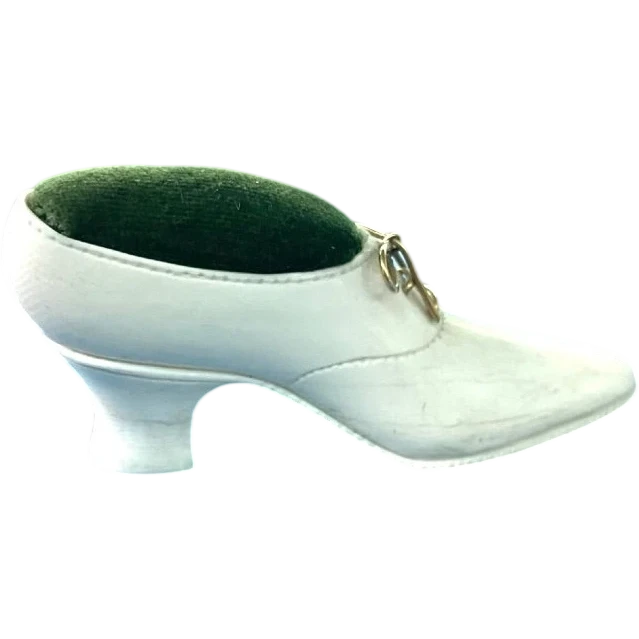 Petite chaussure en ivoire servant de porte-épingles. Détail des lacets dorés.