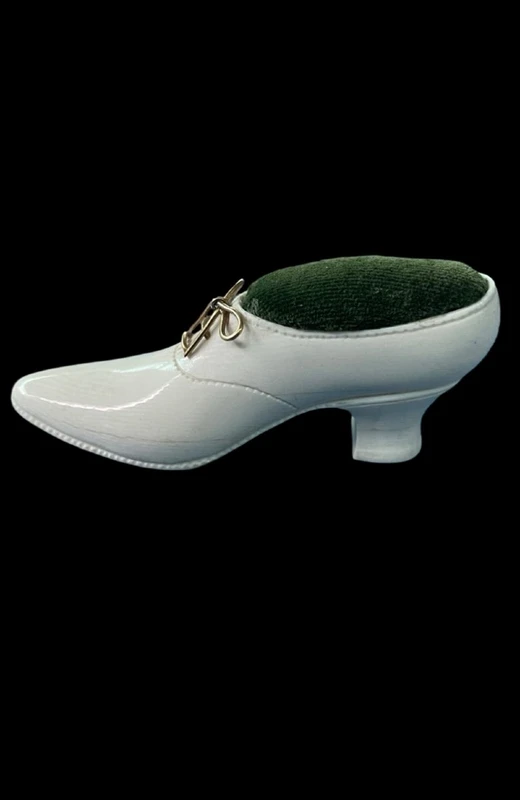 Petite chaussure en ivoire servant de porte-épingles. Détail des lacets dorés.
