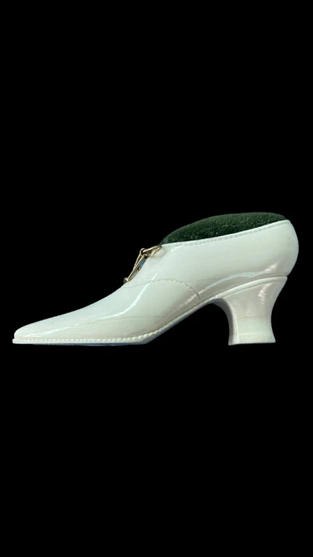 Petite chaussure en ivoire servant de porte-épingles. Détail des lacets dorés.