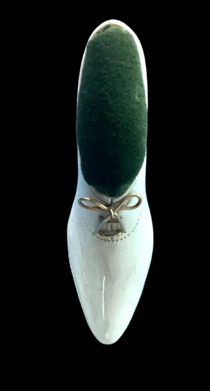 Petite chaussure en ivoire servant de porte-épingles. Détail des lacets dorés.