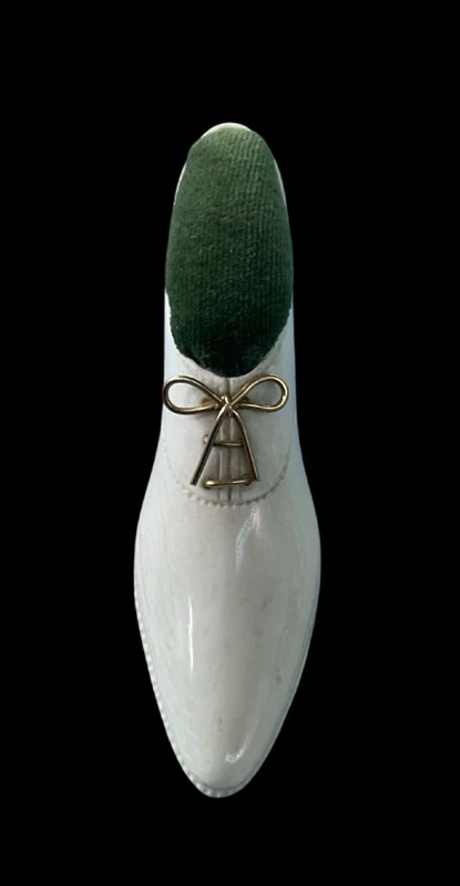 Petite chaussure en ivoire servant de porte-épingles. Détail des lacets dorés.