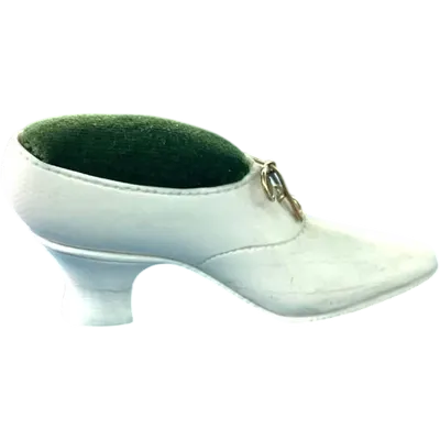 Petite chaussure en ivoire servant de porte-épingles. Détail des lacets dorés.