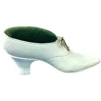 Petite chaussure en ivoire servant de porte-épingles. Détail des lacets dorés.